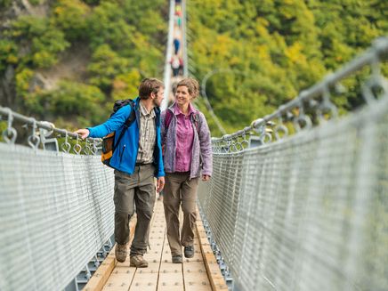 Hängeseilbrücke Geierlay Auf dem Bild befindet sich ein Herr und eine Frau die gerade über die Hängeseilbrücke Geierlay in Sosberg gehen.
