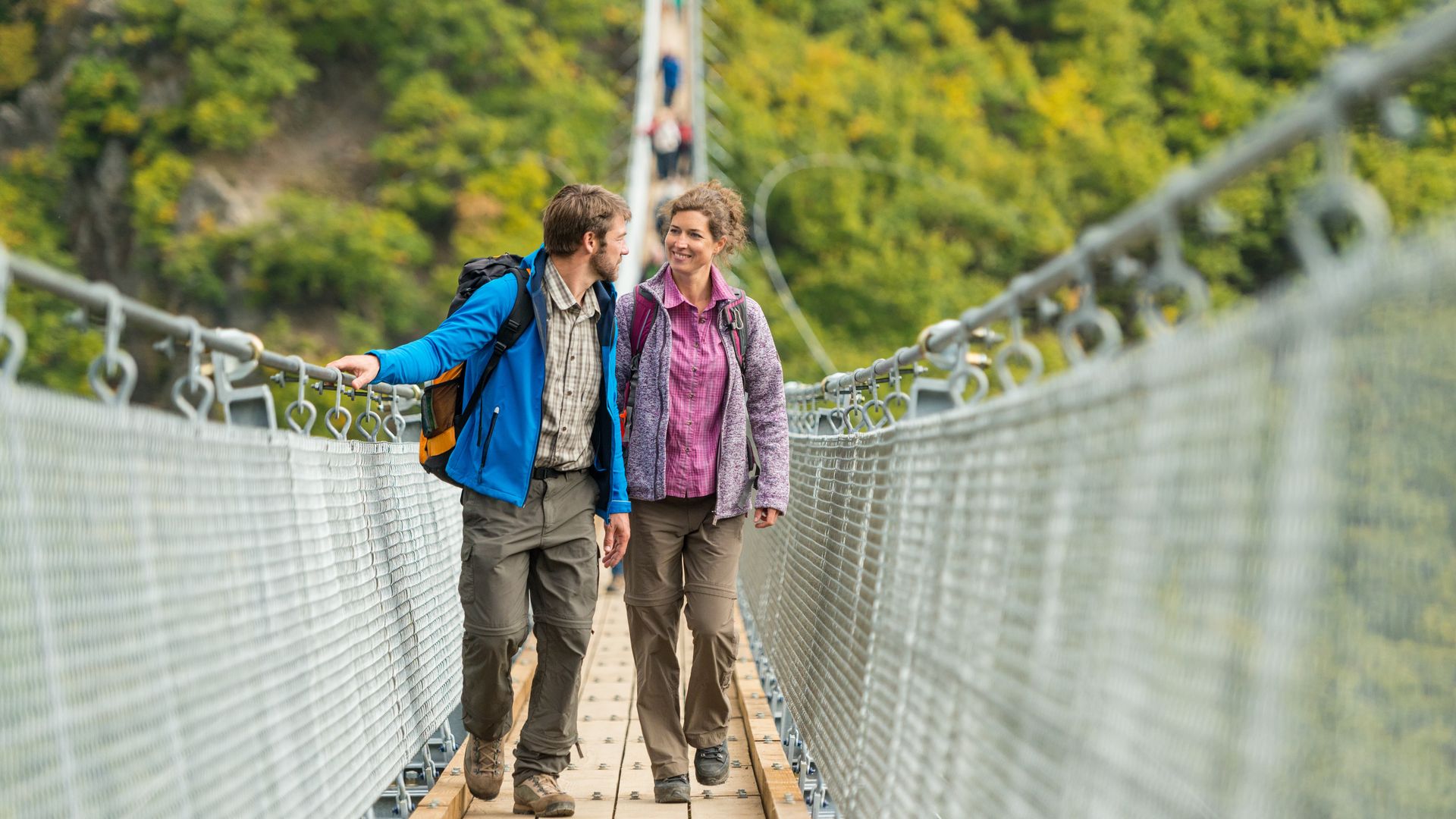 Hängeseilbrücke Geierlay Auf dem Bild befindet sich ein Herr und eine Frau die gerade über die Hängeseilbrücke Geierlay in Sosberg gehen.
