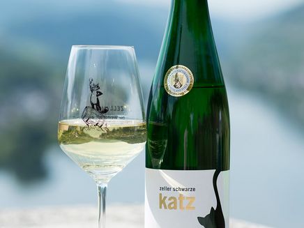 Wein Auf dem Bild befindet sich ein Weinglas und eine Weinflasche, auf denen jeweils das Logo der Zeller Schwarze Katz abgebildet ist.