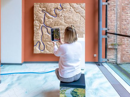 Inspirationsraum Auf dem Bild sieht man das neue Wandmodell im neu gestalteten Inspirationsraum. Davor sitz eine Frau auf einem Fotohocker und bedient das Tablet.