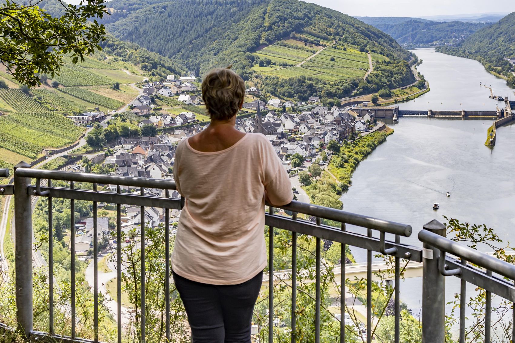 Neefer Petersberg light spot hiking trail The picture shows a woman looking from the vantage point Eulenköpfchen towards the wine village Neef on the left and the barrage.