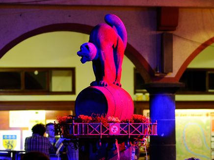 Zeller Schwarze Katz Das Bild zeigt den Zeller Schwarze Katz Brunnen, der mit roten Lichtern beleuchtet ist.