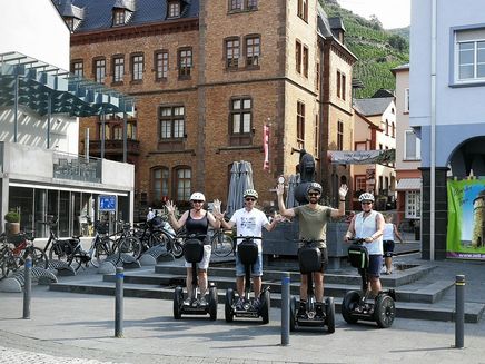 Segway fahren Auf dem Bild befinden sich einige Leute auf einem Segway. Sie stehen in Zell an der Mosel vor dem Zeller Schwarze Katz Brunnen.
