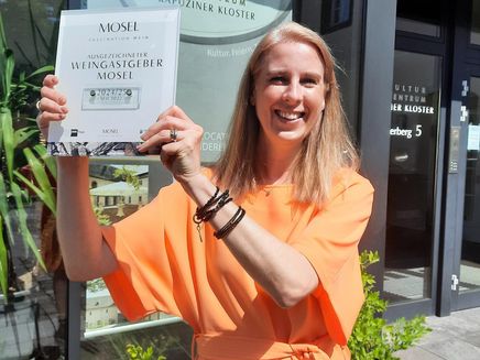 Janine Reichert The picture shows Janine Reichert holding the Mosel Wine Host certificate.