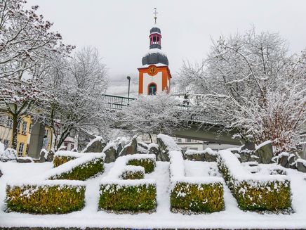 Zell an der Mosel bei Schnee Auf dem Bild befindet sich den Ortsnamen Zell aus Buchsbäumen geformt. Im Hintergrund ist die Kirche von Zell. Es liegt Schnee.