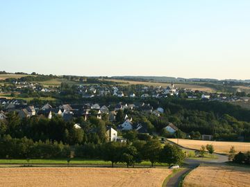 The picture shows a view of Mittelstrimmig. In the foreground you can see a path leading through the village and in the background there are fields.