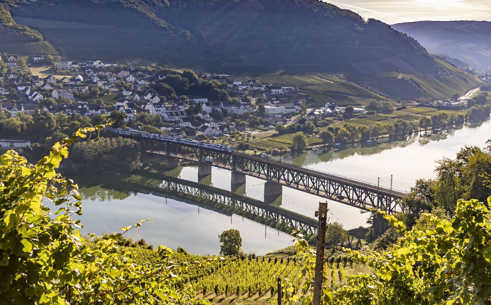 Doppelstockbrücke Das Bild zeigt die Doppelstockbrücke, die die Mosel bei Bullay überkreuzt. Im Hintergrund befindet sich ein Ausschnitt von diesem Moselort sowie Weinberge.