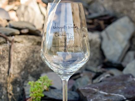 Weinglas Auf dem Bild befindet sich ein Weinglas mit der Aufschrift Gibbert-Pohl. Es wird gerade aus einer Weinflasche Wein ins Glas geschüttet.