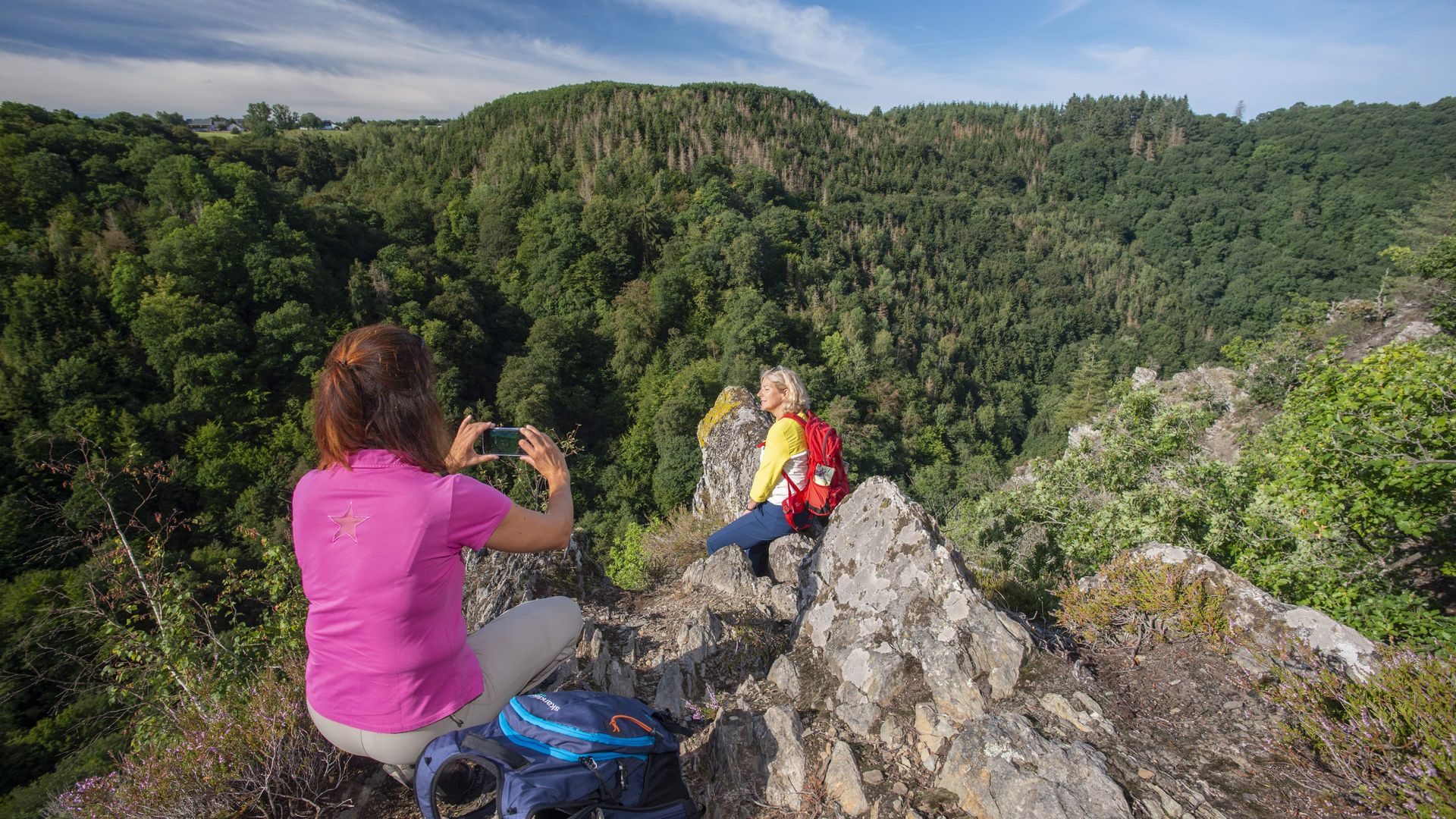 Traumschleife Altlayer Schweiz Auf dem Bild befinden sich zwei Frauen auf der Traumschleife Altlayer Schweiz. Eine Frau macht von der anderen ein Foto am Rand des Felsens.