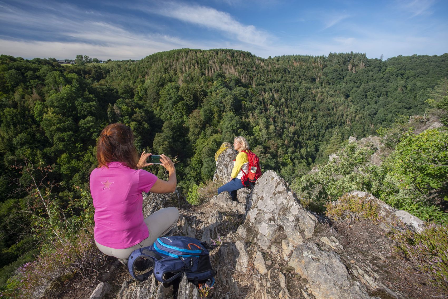 Traumschleife Altlayer Schweiz In the picture, there are two women on the Altlayer Schweiz dream loop. One woman is taking a photo of the other at the edge of the rock.